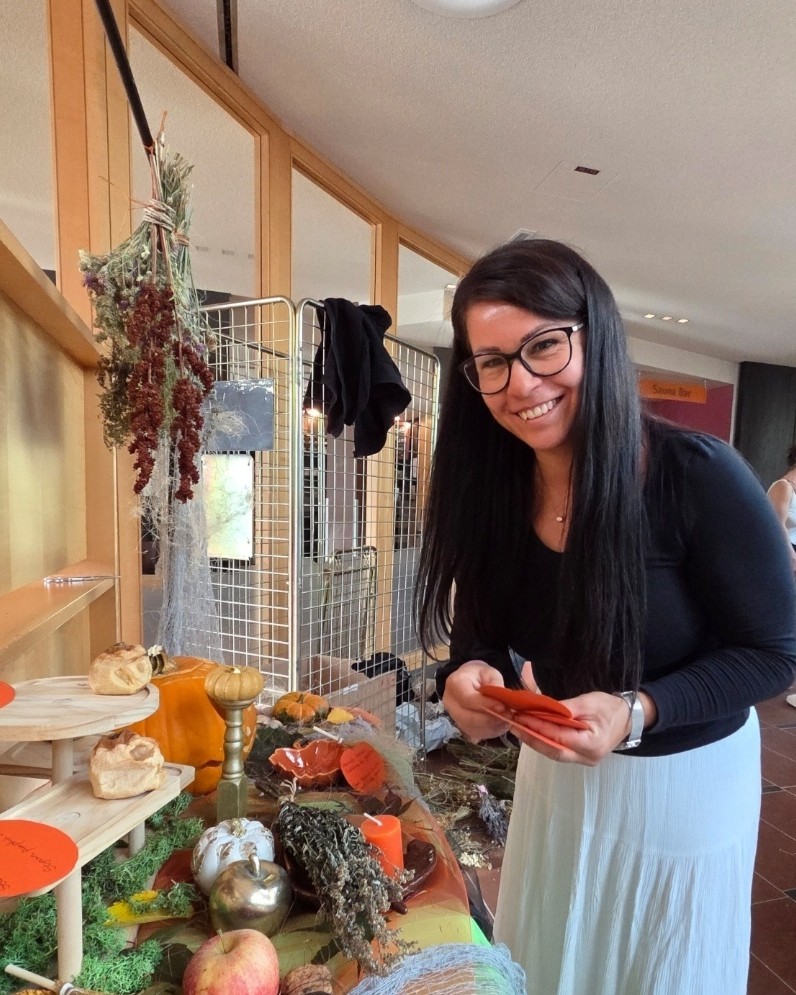 Őszi-halloweeni fogadópult asztaldísze faragott töklámpással, dísz tökökkel, szárított kukoricával, gyertyával és pókhálószerű hálóval